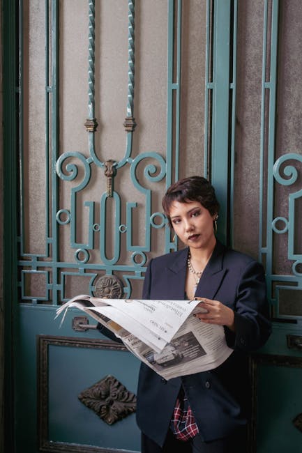A fashionable woman in a blazer reads a newspaper against an elegant door backdrop.